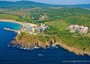 Aerial view of coastal resort with palm trees, pool, and beachfront villas